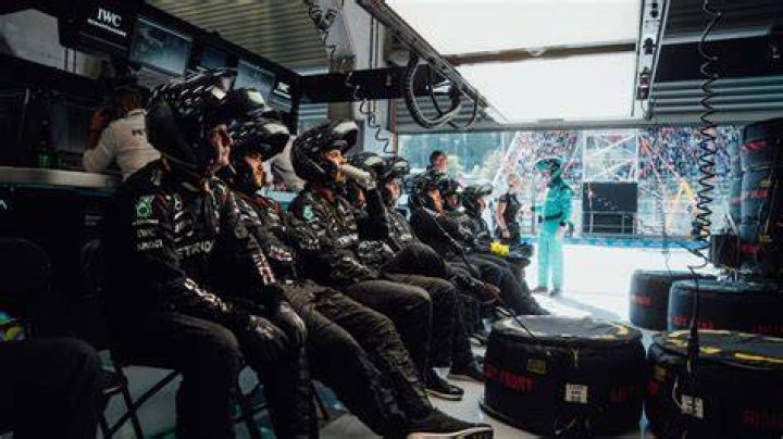 Why do F1 teams wear headphones in meetings?